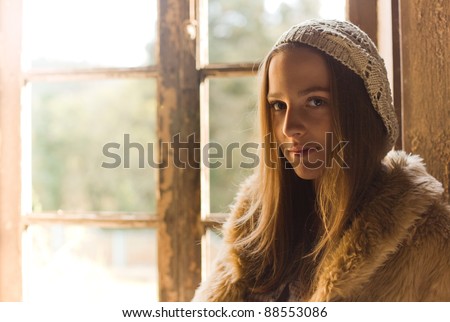 Beautiful young woman next to the window with soft light in the face