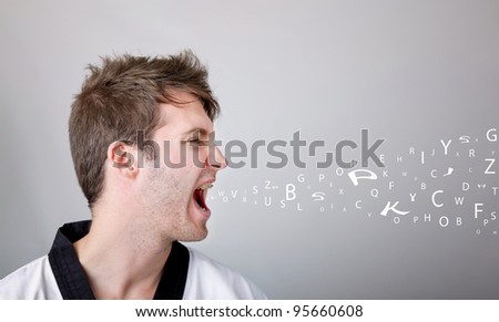 Young martial arts man shouting over gray background