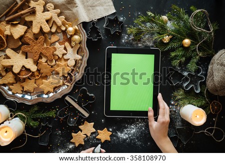woman with tablet pc computer making gingerbread houses at home