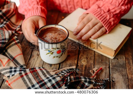 Woman holding cup of hot chocolate. Hot Chocolate in wooden table.  Woman having a cup of coffe. Rose hip tea and fresh rose hips.
Autumn composition.