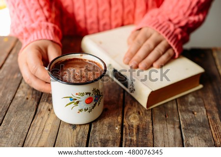 Woman holding cup of hot chocolate. Hot Chocolate in wooden table.  Woman having a cup of coffe. Rose hip tea and fresh rose hips.\
Autumn composition.