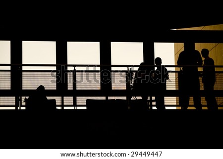 A group of people meeting in a modern building silhouetted against the warm sunset glow.