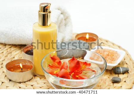 Bowl with red flower , salt and a cream for a bath with candles and a towel-beauty treatment