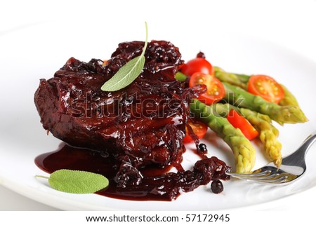 Steak sauce with wine and onions, served with asparagus on a white plate