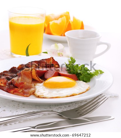 Breakfast with bacon, fried egg and orange juice on white isolated background