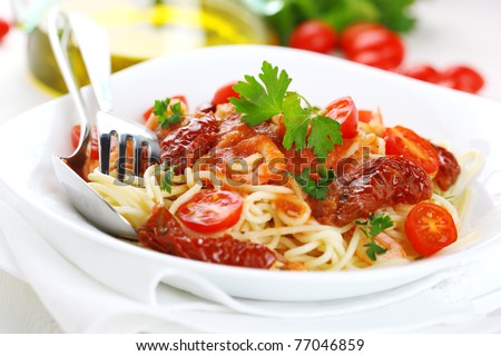 Spaghetti with tomato sauce, sun dried tomato and shrimps on white plate