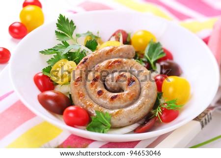 Grilled sausages with salad of tomato-colored on white plate