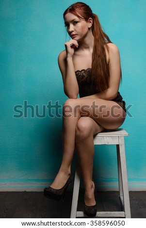 girl in underwear sitting on a stool against the blue wall