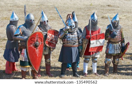 group of the people dressed in an armor of medieval soldiers up in arms