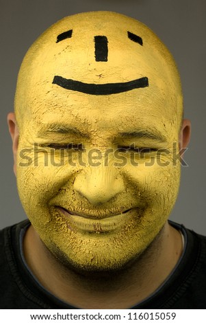 Painted face, black and yellow paint on happy face. Cracked paint. Smiley emoticon drawn od head. part of large series of paintesd tribal portraits