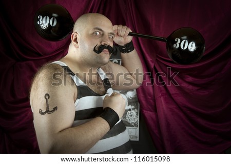 Vintage circus strongman holding big 300 lbs weights. Bald strong man in striped t- shirt lifting heavy weights. Vintage cinema circus scene. Part of larger vintage collection.