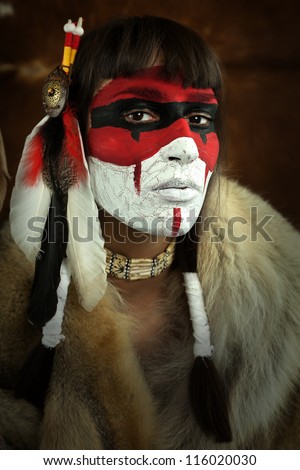 Native american woman portrait with painted face. Young beautiful woman in native american costume with wolf fur and war mask on her face