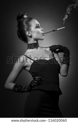 Beautiful girl  portrait in retro style. Glamorous woman in black outfit smoking a cigarette