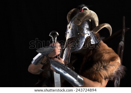 Muscular man in viking costume with horned helmet , shield and sword