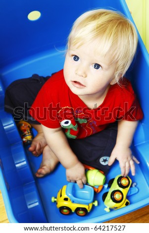 Little boy seating in blue box and playing with toys