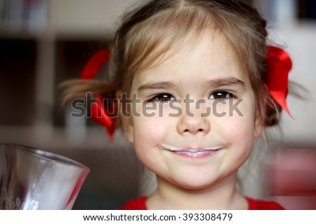 Close-up portrait of gorgeous little girl with milk mustache drinking a glass of milk at home, food and drink concept, healthy food, indoor