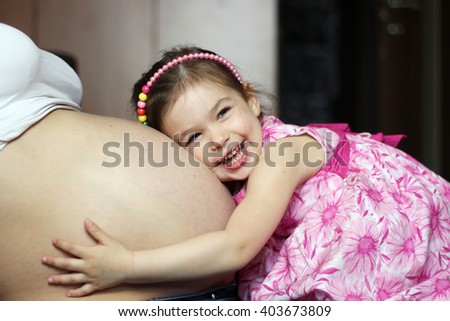 Happy kid girl hugging pregnant mother\'s belly, pregnancy and new life concept