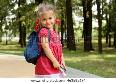 Beautiful little girl with backpack walking in the park ready back to school, fall outdoors, education concept
