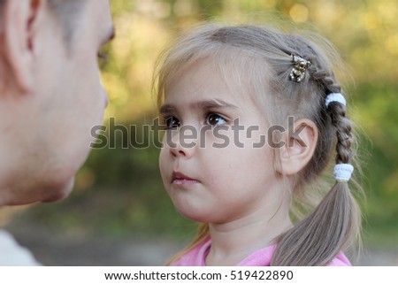 Pretty small girl with two braids looking on her father seriously to hear something important, autumn outdoor