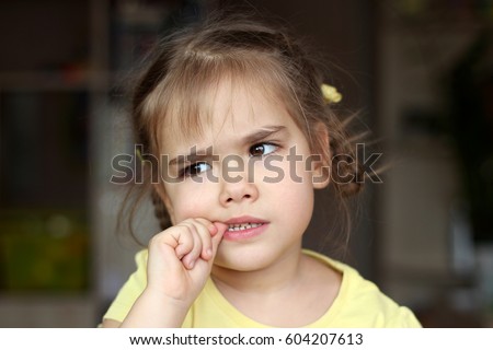 Beautiful girl nervously biting her nails, childhood and family concept, emotional child portrait, indoor closeup