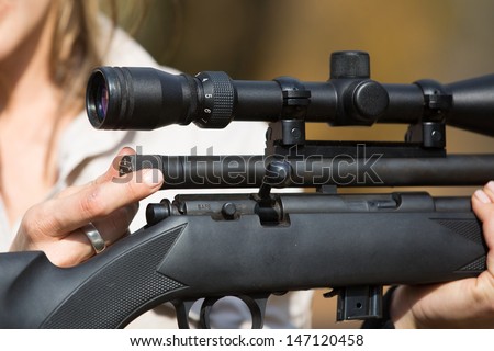 A close up of a caucasian woman setting the power level of a darting rifle
