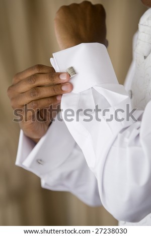 A black man fastening a cuff-link before getting married