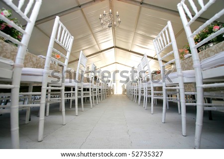 stock photo Two rows of chairs at a wedding reception in a massive tent