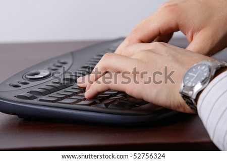 A low side-on photo of a caucasian man typing on a computer keyboard, showing his hands only