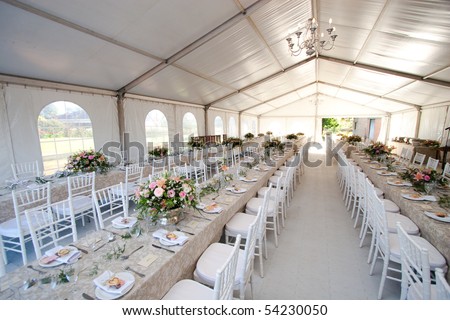 stock photo The inside of a massive white wedding tent with tables and 