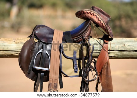 Horse riding gear, including saddle, bag and leather hat, hanging over a wooden pole