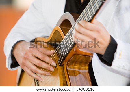 A horizontal photo of a caucasian musician playing a classical guitar at a wedding reception