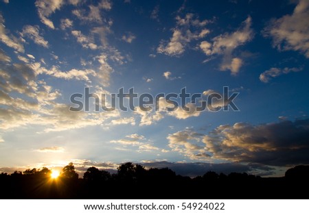 A stunning sunset photo with fluffy white clouds and a blue sky