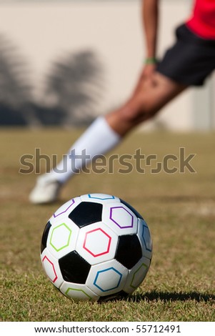 Football with man stretching in background