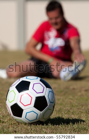 Football with man stretching in background