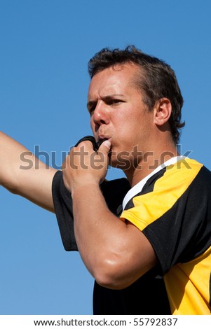 A referee blowing the whistle outdoors