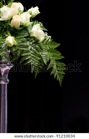 A bouquet of white roses in a silver stand with a black background