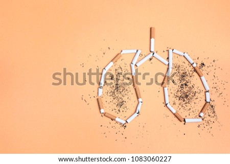 Broken cigarettes and tobacco in the form of lungs on yellow background. No smoking concept.  Flat lay, top view with copy space.