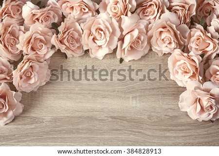 Border of pink roses on a wooden background with empty space for text. Top view with copy space