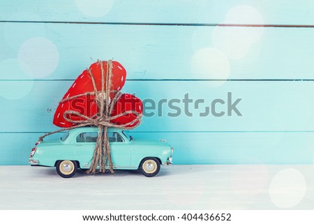 Background with miniature blue toy car carrying a heart on blue painted wooden planks. Place for text.