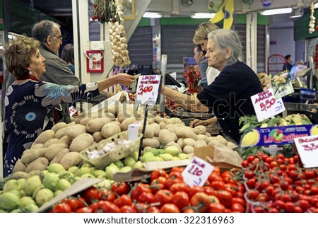 ROME, ITALY - 24 SEPTEMBER 2015: A customer, left, pays for her purchase from a fruit and vegetable stall inside an indoor market in Rome, Italy