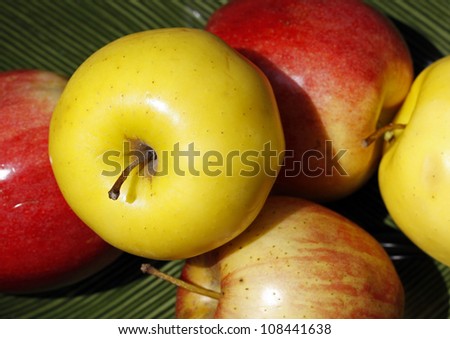 Yellow and red apples, focus on yellow apple in foreground.