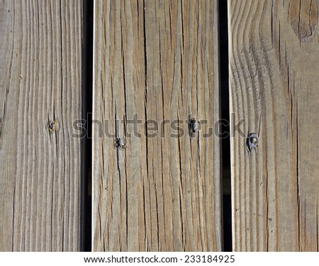 Closeup of wooden boards with nails, wood grain, and vertical spaces between boards.
