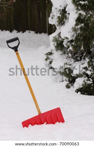 Red snow shovel standing up in deep snow.
