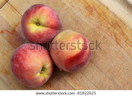 Three peaches on cutting board.
