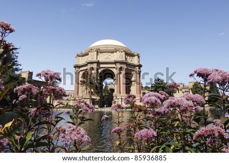 Palace of Fine Arts, San Francisco,California, looking across pond to dome pink flowers in foreground,blue sky in background.