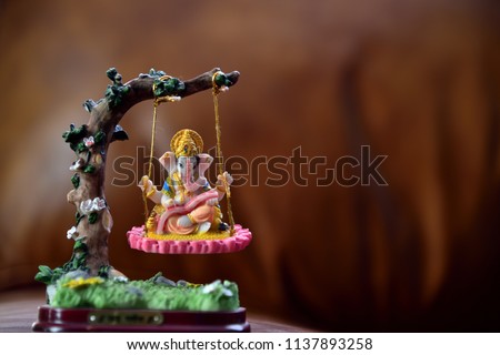 Hindu God-Ganesha in art form sitting on a swing. text translation = Jai Ganesha (Hindu god name). Hindu Lord Ganesha, a symbol of success, trouble remover and prosperity