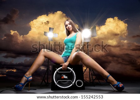 Art Beauty Portrait of Beautiful Girl seating on loudspeaker with sunset background