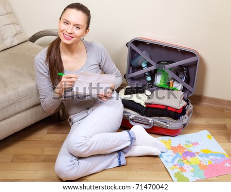 Young woman packing a suitcase at home going on holiday