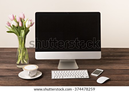 Workspace with computer at home or in the studio , a desk with flowers.