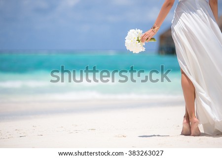 Young woman with bouquet of flowers on the beach.